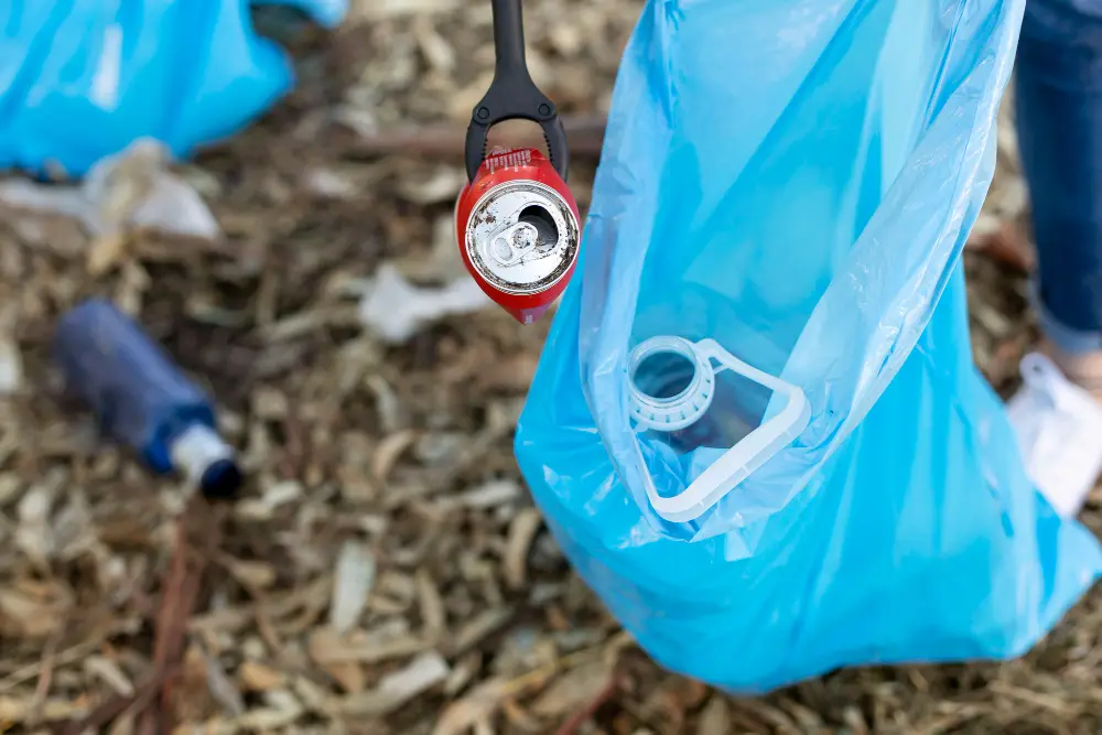 Person collecting an aluminium drink can for recycling during a community clean-up in Adelaide to reduce landfill waste.