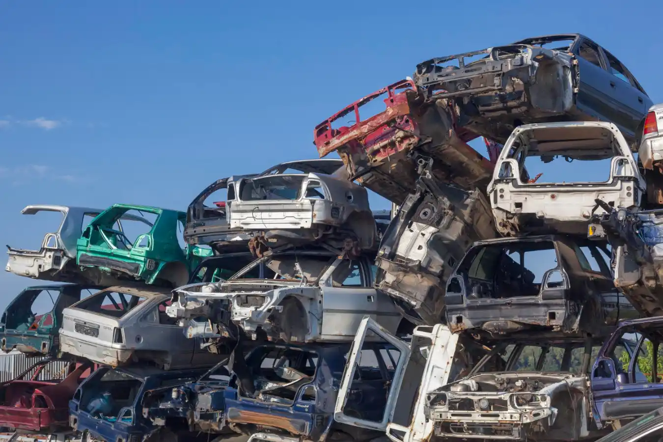 Stacked scrap vehicles at a metal recycling yard ready for processing.